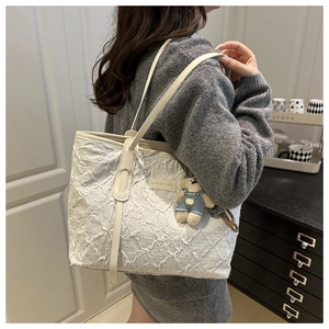 Vue détaillée du sac cabas crème avec texture gaufrée et pendentif ours en jean