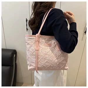 Dettaglio del ricamo floreale rosa e della trama stropicciata su una grande borsa tote