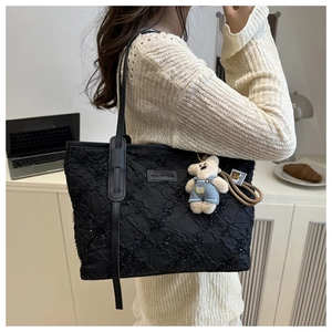 Detail of black pleated tote bag with sequins, leather strap and plush bear charm
