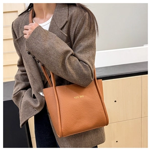Detailaufnahme der braunen Tote Bag aus genarbtem Leder mit gelbem Textaufdruck