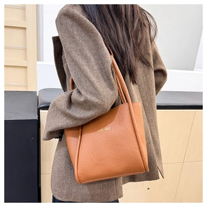 Nahaufnahme der braunen Tote Bag aus Leder mit Litschimuster zu einem schicken Blazer