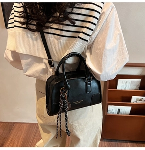 Dettaglio della borsa a bauletto retrò nera con scritte moda e ciondolo a nodo decorativo
