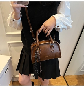 Detail view of dark brown faux leather crossbody bag with decorative striped silk scarf