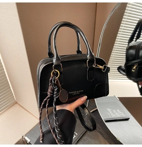 Close-up of black Boston bag with gold hardware and stylish tennis racket pendant