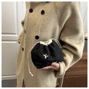 Close-up of black quilted drawstring makeup bag with white embroidery detail