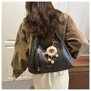 Detail of black leather crescent bag with sheep plush charm and fashion logo print
