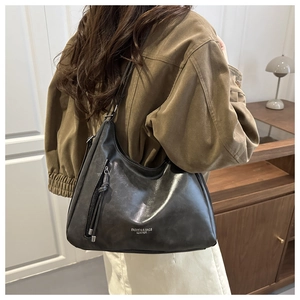 Detail of black leather hobo bag featuring silver fashion text and side zipper detail