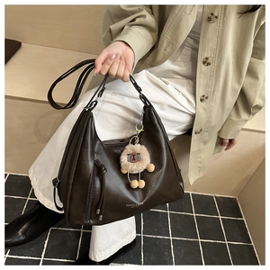 Close-up of deep brown crescent bag with long fringe zipper and cute lamb pendant