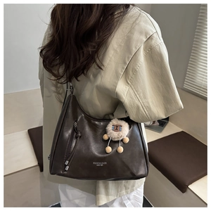 Close-up of a large brown leather shoulder bag with cute sheep charm and logo detail
