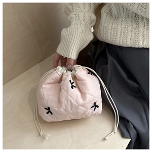 Close-up of pink quilted bucket bag with black bow embroidery and drawstring closure