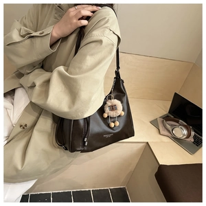 Detail of dark brown leather tote bag with fashion lettering and cute plush pendant