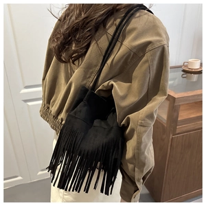 Gros plan du sac à main noir à franges porté par un mannequin dans un décor vintage