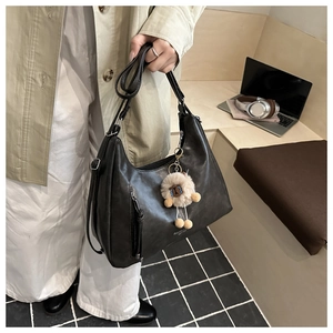 Detail of black vintage PU leather hobo bag with alpaca charm on a wooden desk setup
