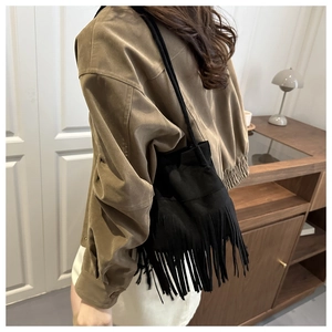 Détail d'un sac seau noir à franges en daim mat dans un style bohème rétro élégant