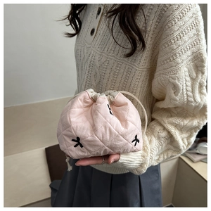 Close-up of pink quilted makeup bag with black bow embroidery and drawstring closure