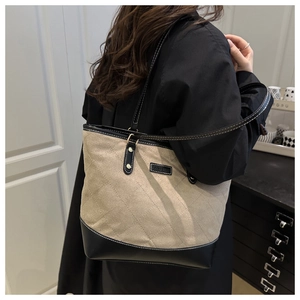 Detailansicht der gesteppten Canvas-Tasche mit schwarzen Lederriemen am Modell