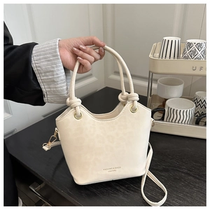 Detail of white leopard embossed bucket bag with unique knot handle and gold eyelets