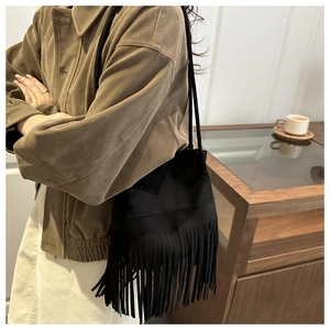 Détails d'un sac seau bohème en daim noir avec de longues franges et une bandoulière corde