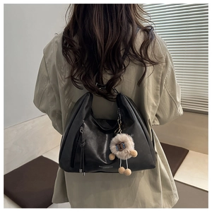 Detail of black leather hobo bag with fringe zipper and a cute brown plush bear charm