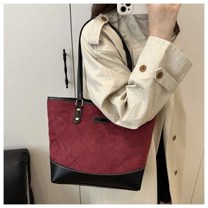 Close-up of a large burgundy tote bag with quilted pattern and a sleek black fashion label
