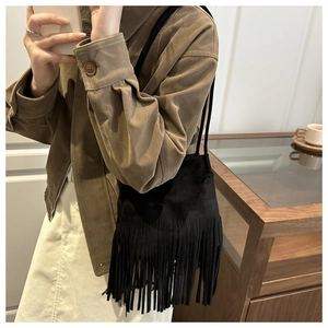 Gros plan du sac seau noir à franges avec texture en daim doux porté par un mannequin