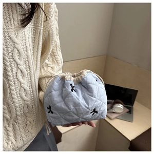 Primo piano della borsa trapuntata azzurra con ricamo a fiocco nero e chiusura a cordoncino