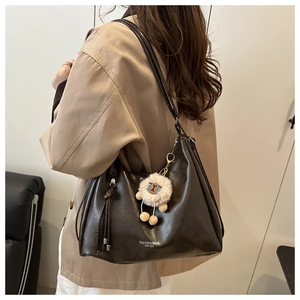 Detail of dark brown leather tote with fringe tassel and plush sheep pendant charm