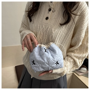 Close-up of light blue quilted drawstring pouch with black bow embroidery details