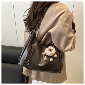 Detail of dark brown leather tote with tassel zipper and sheep plush charm on model