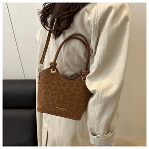 Détail du sac seau léopard avec inscription dorée et texture mate sur la bandoulière