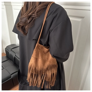 Vue détaillée du sac seau en daim marron caramel avec de longues franges sur un modèle