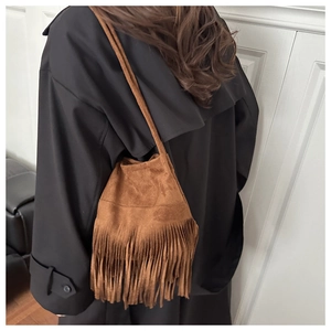 Détail d'un sac bandoulière en daim marron avec franges et style bohème vintage