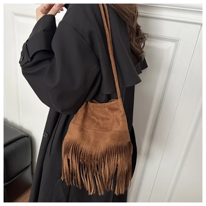 Gros plan du sac bandoulière en daim marron avec de longues franges sur un mannequin