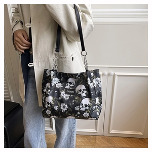 Close-up of personalized skull and white floral print on a black shoulder tote bag.