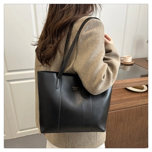 Détail d'un sac cabas en cuir PU noir avec lettrage doré dans un décor de vie