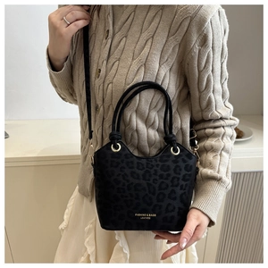 Detail of black leopard print bucket bag with gold ring hardware and logo texture
