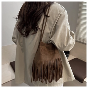 Détail du sac seau en daim marron avec de longues franges et un style bohème chic
