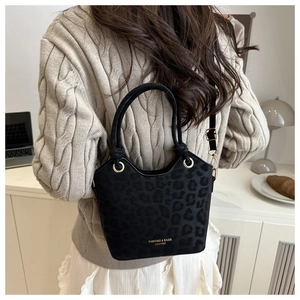 Detail view of black leopard print bucket bag with gold hardware and shoulder strap
