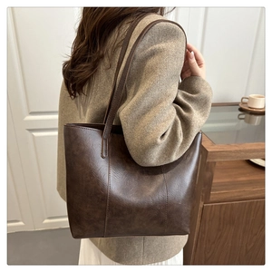Grand sac cabas vintage en cuir marron foncé porté par un mannequin dans un décor naturel