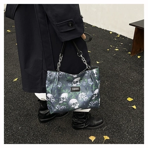 Detail shot of a gothic skull and floral print tote bag with metal chain straps.