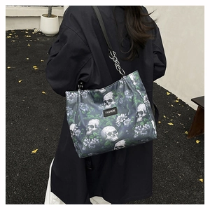Detail of grey skull tote bag with floral prints and metal chain strap on model
