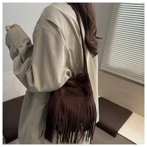 Détail d'un sac bandoulière en daim marron foncé avec de longues franges de style bohème