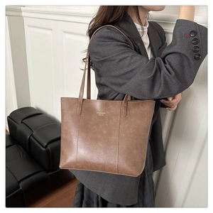 Close-up of brown faux leather tote bag with Fashion Bags text on a gray blazer model