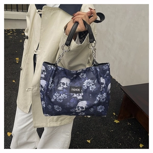Close-up view of stylish skull and flower print tote bag held by a model outdoors