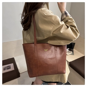 Brown vintage faux leather tote bag with long strap shown on model in khaki coat