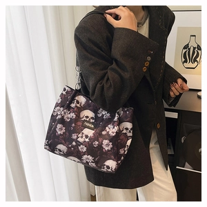 Close-up of a stylish tote bag with a dark skull and floral pattern carried by a model.