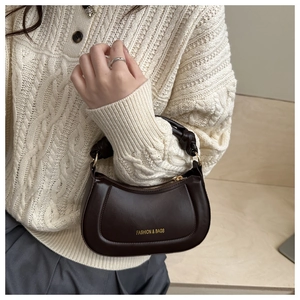 Dark brown crescent bag worn with beige sweater showing elegant autumn style
