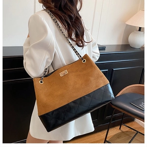 Detail of two-tone tote bag featuring black quilted pattern and brown suede top with twist lock