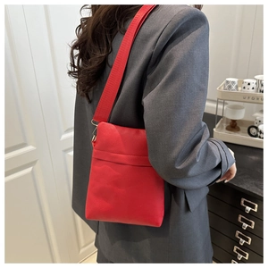 Lifestyle view of a red pebble leather underarm bag with adjustable wide fabric strap