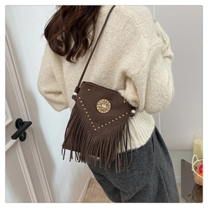 Detail of brown suede crossbody bag with vintage rhinestones, metal rivets, and long tassels